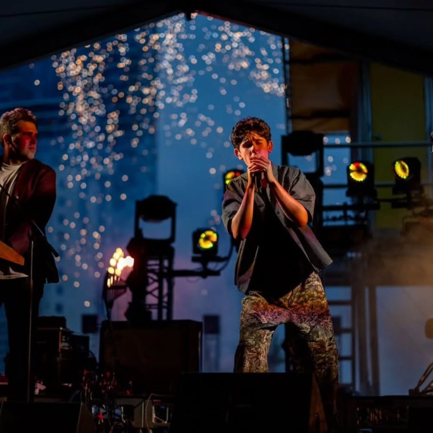 Vocalist performing on stage with close proximity firework effects overhead