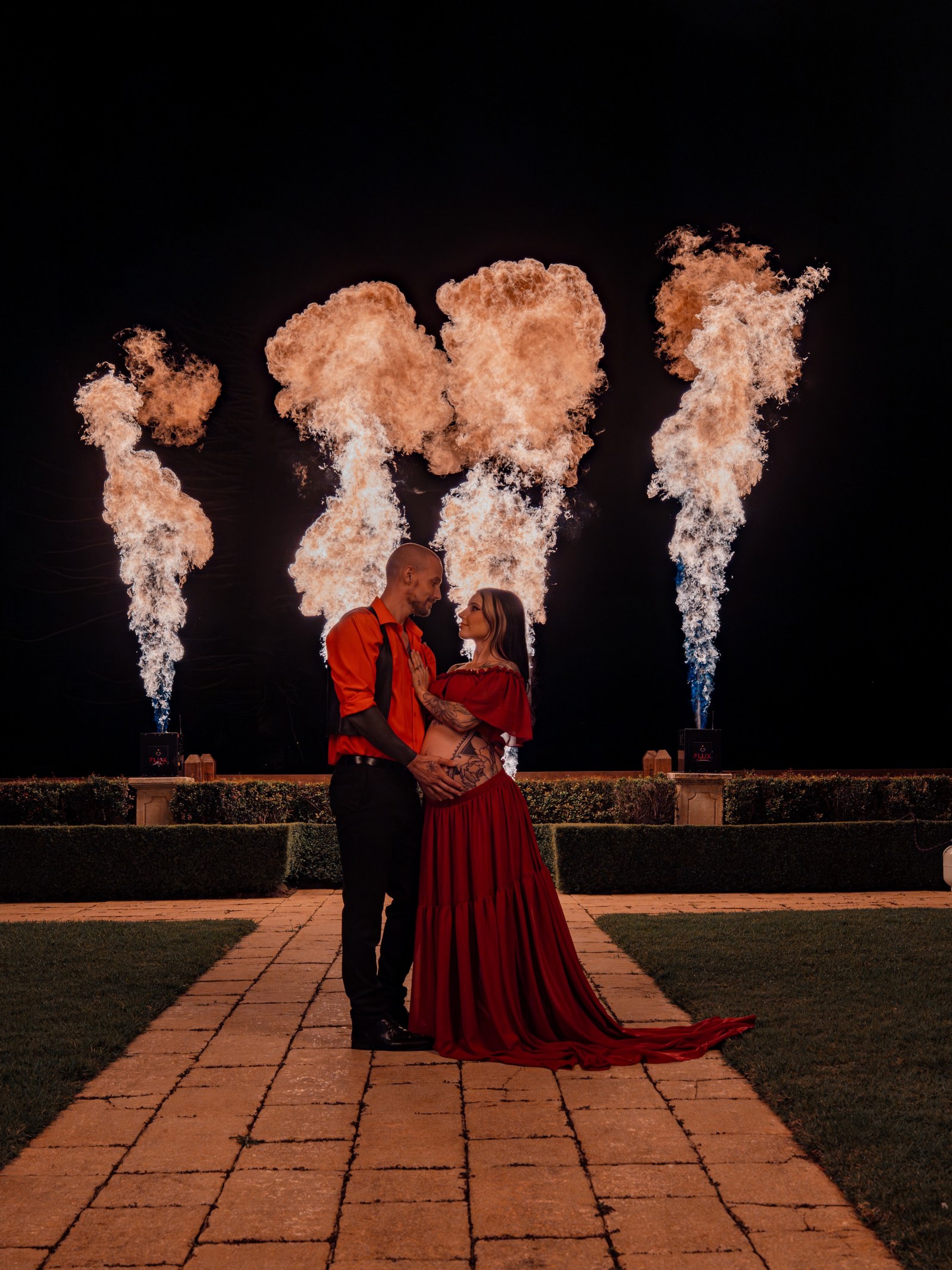 Couple embracing in front of four tall flame projection bursts