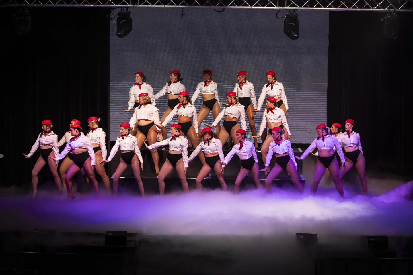 Dance troupe performing on stage with low fog rolling across the floor