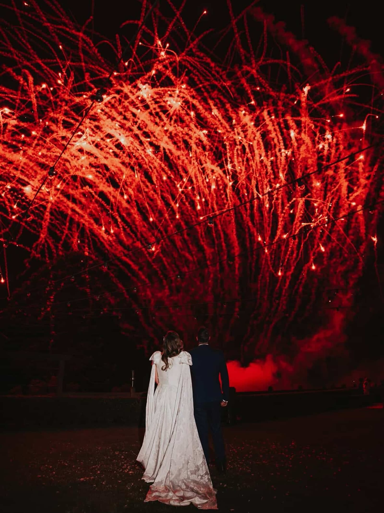 Wedding couple under red willow-style fireworks canopy