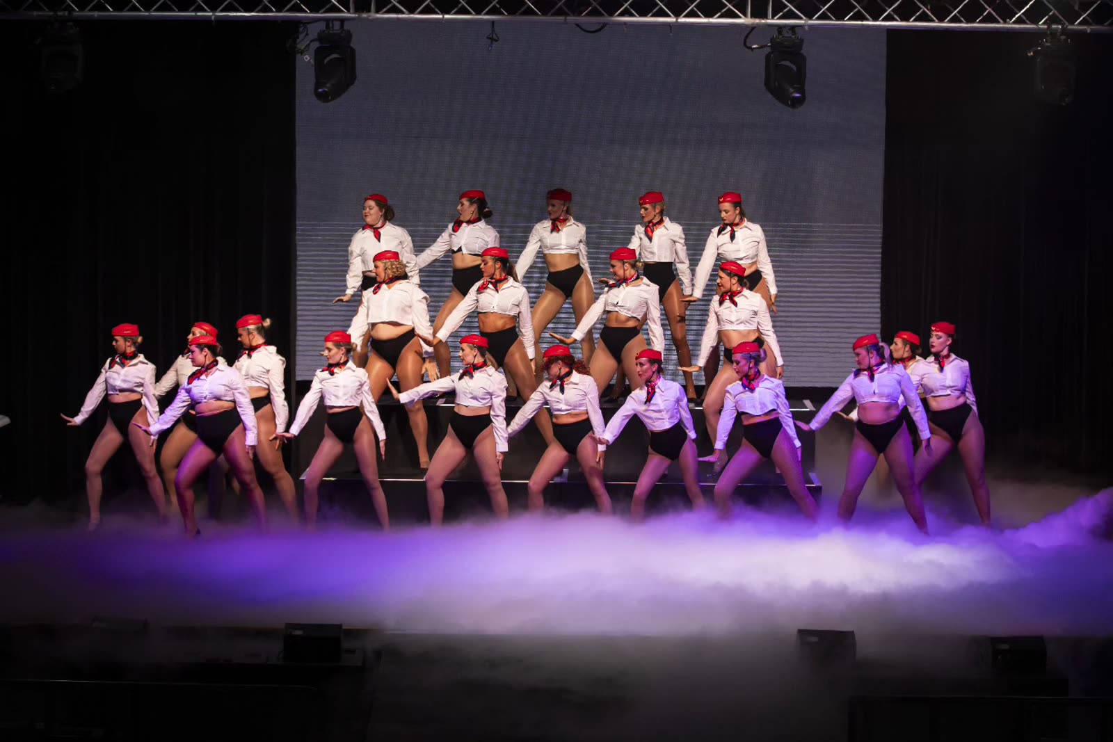 Dance troupe performing on stage with low fog effect